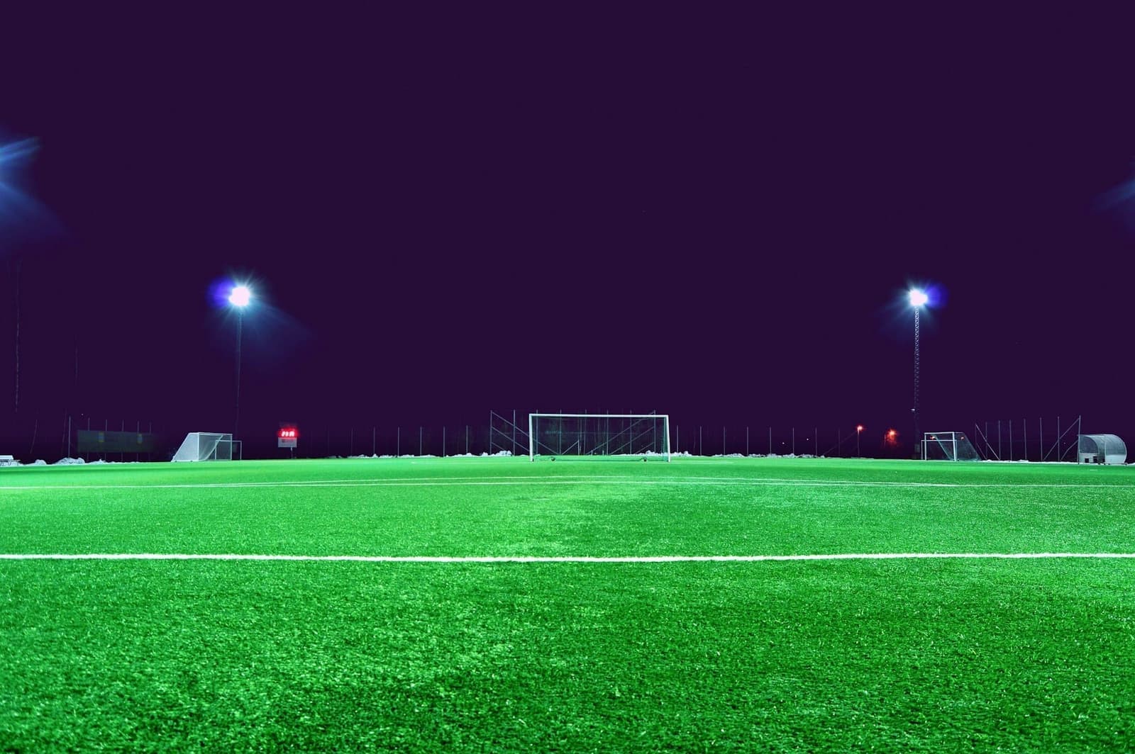 Verlicht voetbalveld met doel bij avond
