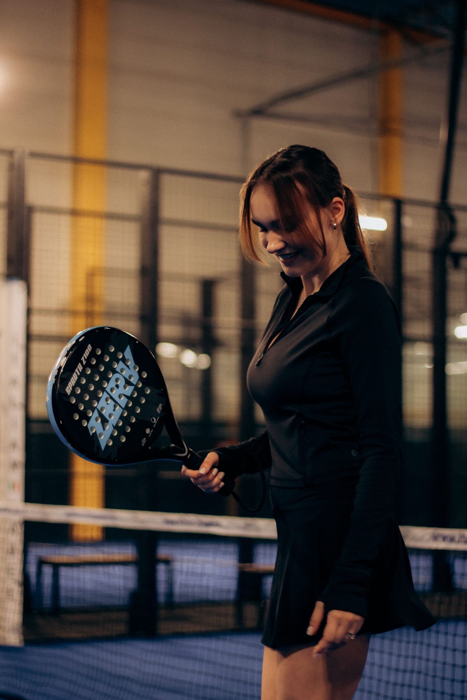 Vrouw met een padelracket in een donkere padelhal