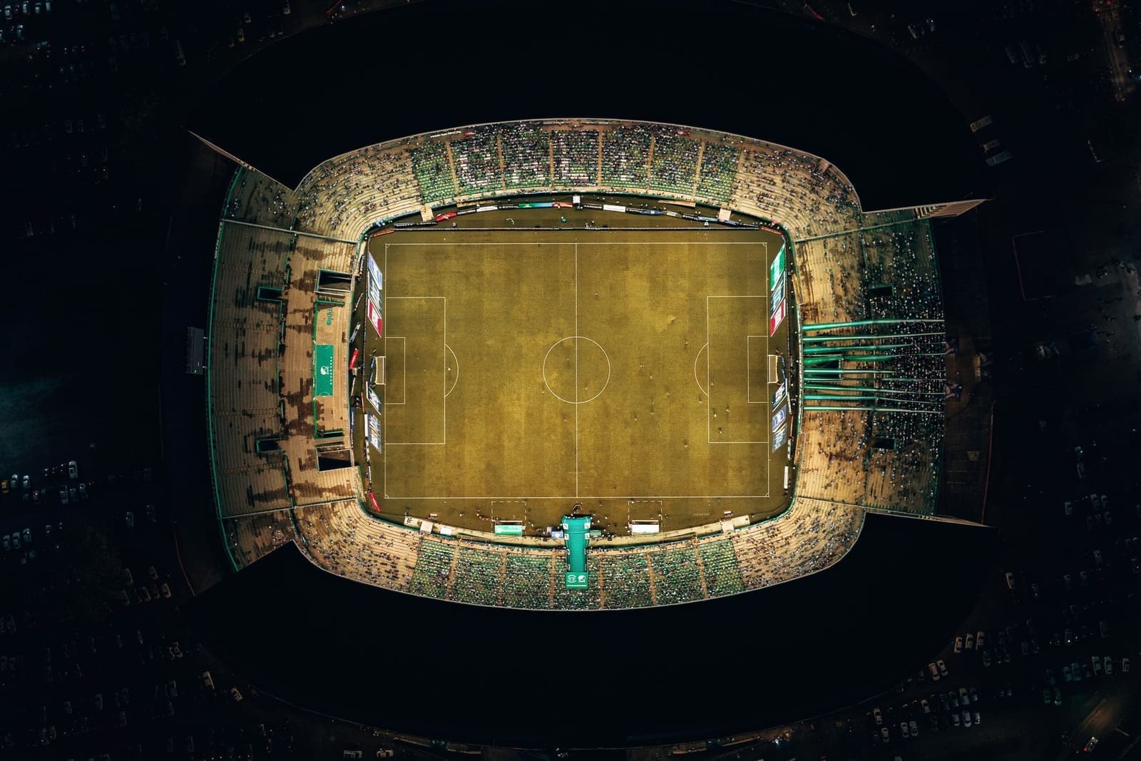 Verlicht voetbalstadion bij nacht, recht van boven gezien