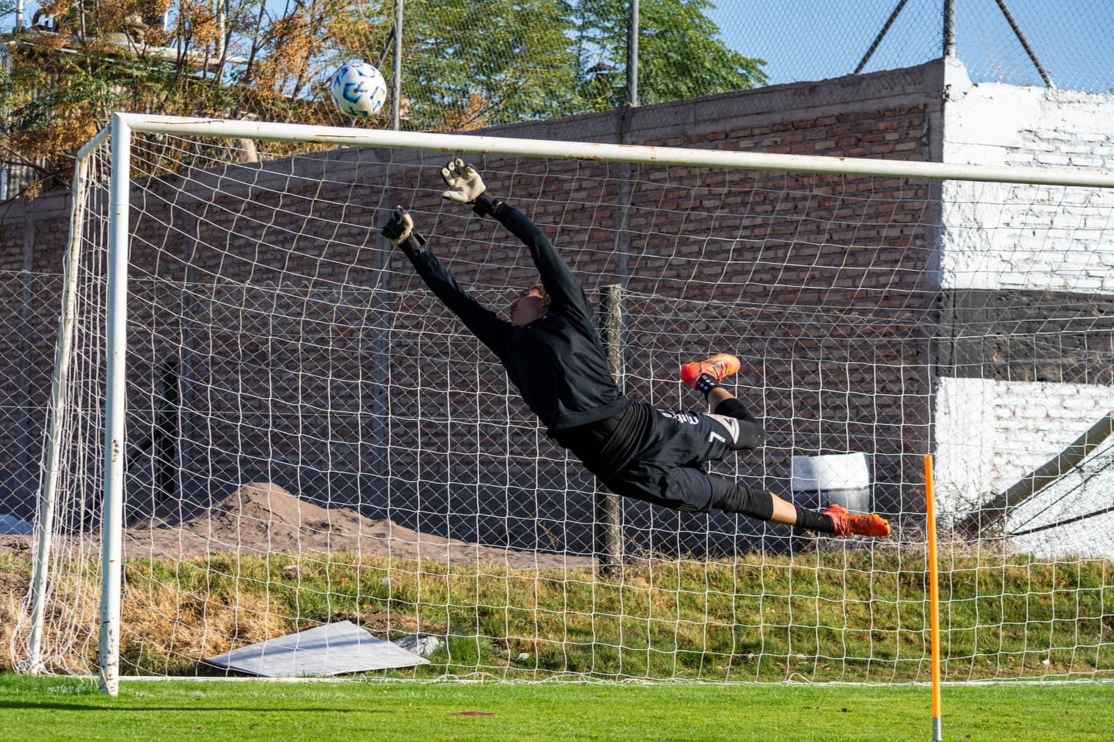 Jonge keeper duikt naar de bal