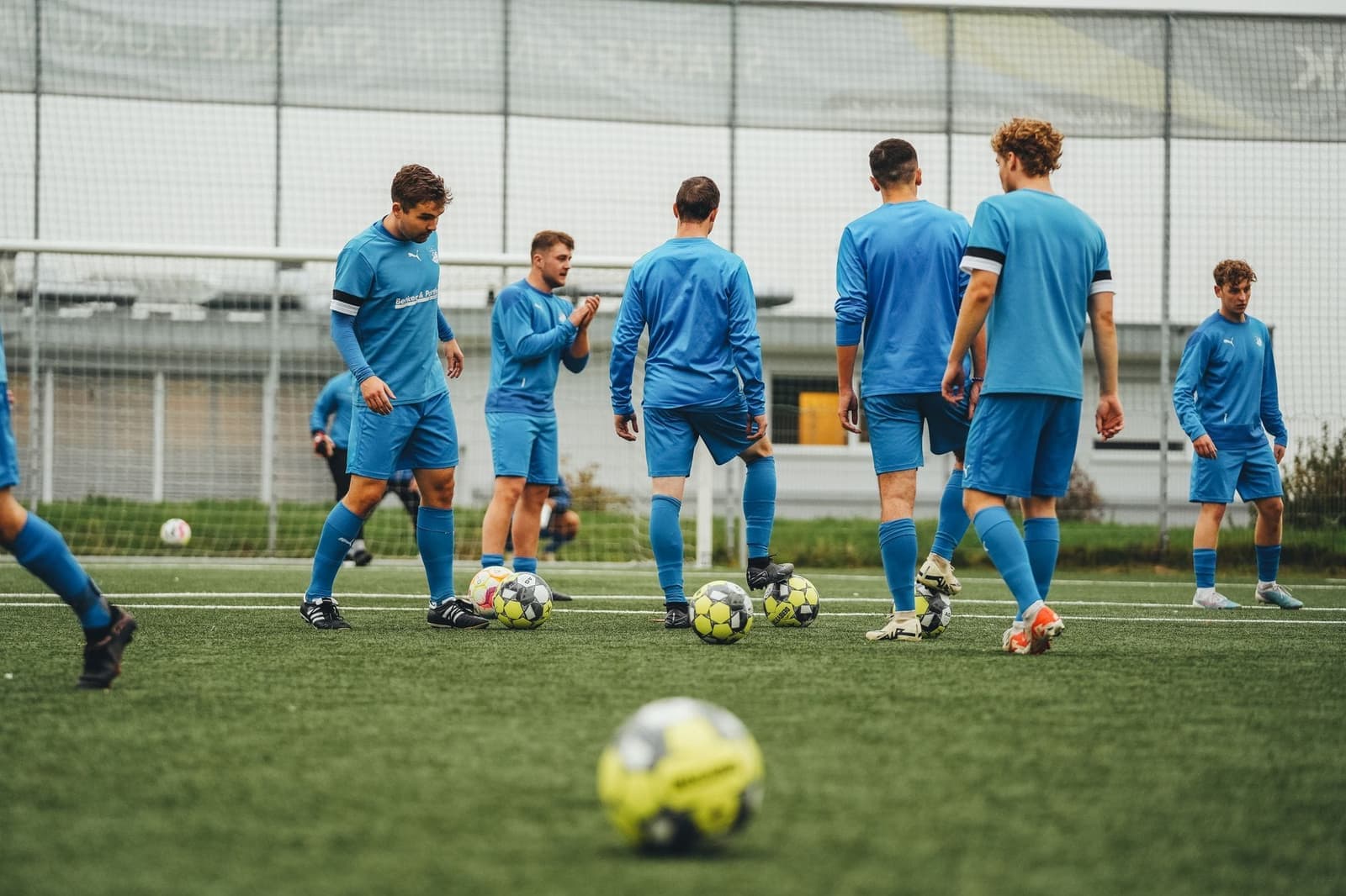 Jeugdteam in lichtblauw tenue traint met ballen op het veld