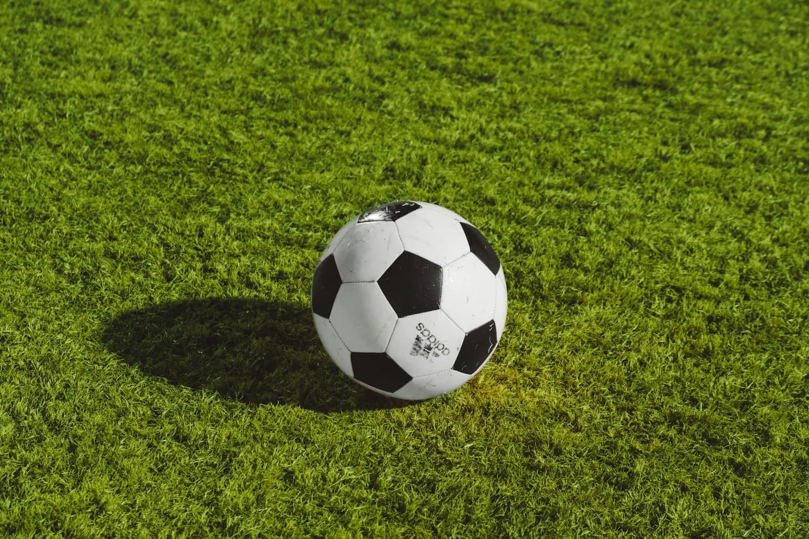Voetbal op het gras in laag zonlicht