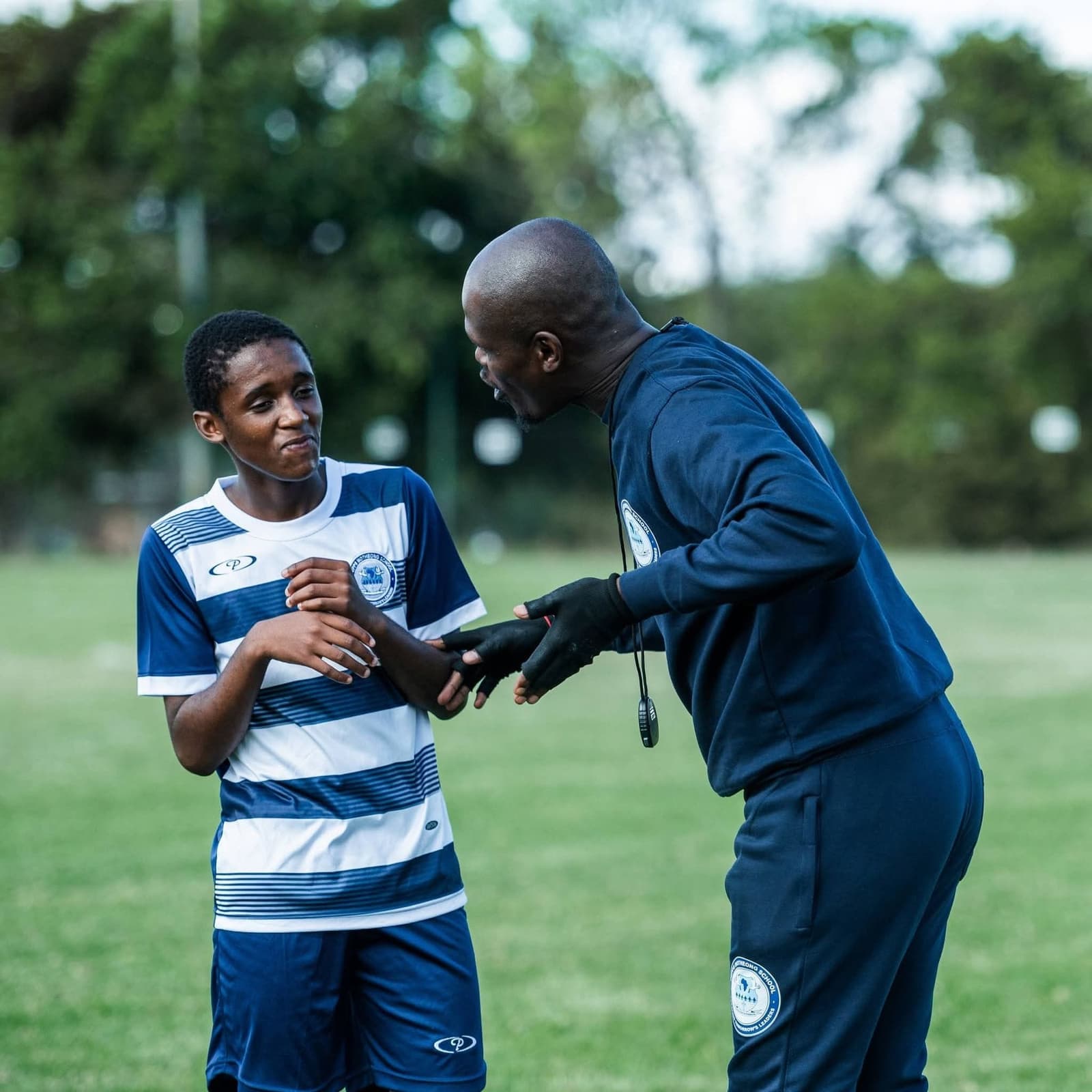 Trainer in gesprek met een jonge voetballer op het trainingsveld