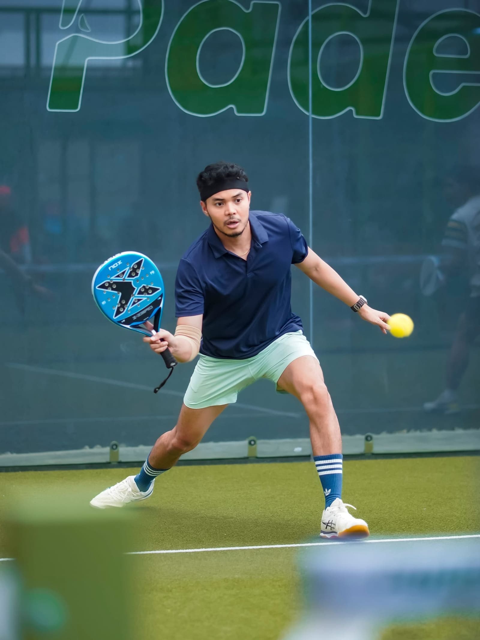 Jonge padelspeler slaat een bal op een indoorbaan