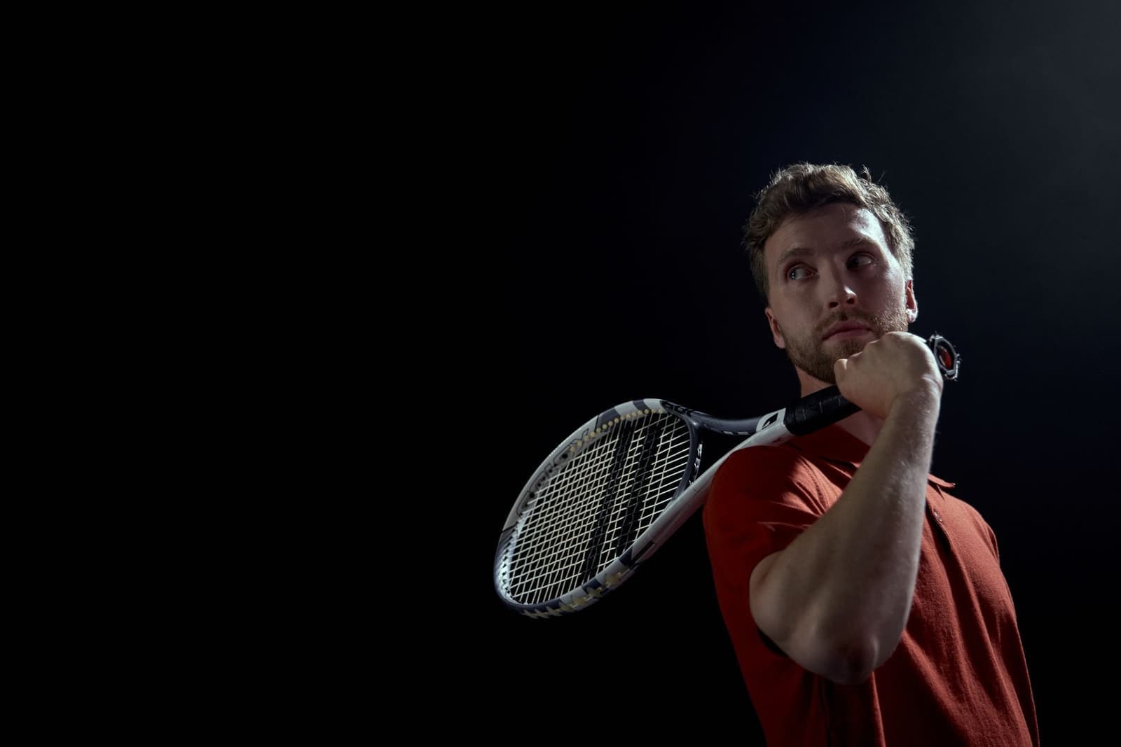 Tennisser met racket tegen een donkere achtergrond